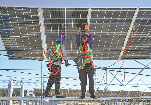 Para pekerja memasang panel fotovoltaik sebagai bagian dari proyek pengendalian penggurunan di Gurun Kubuqi di wilayah otonomi Mongolia Dalam, China Utara, pada Juli 2023. LIU LEI/XINHUA